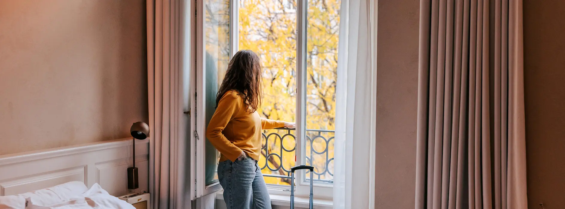 Person standing at an open window in the hotel room