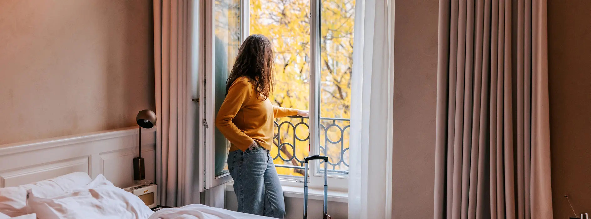 Person standing at an open window in the hotel room