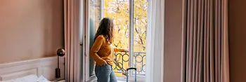 Persona de pie junto a una ventana abierta en la habitación del hotel