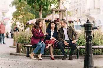 3 Personen sitzen auf einer Bank und lachen