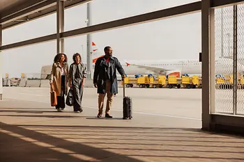 People with hand luggage in the outdoor area of Vienna Airport on the way to the terminal